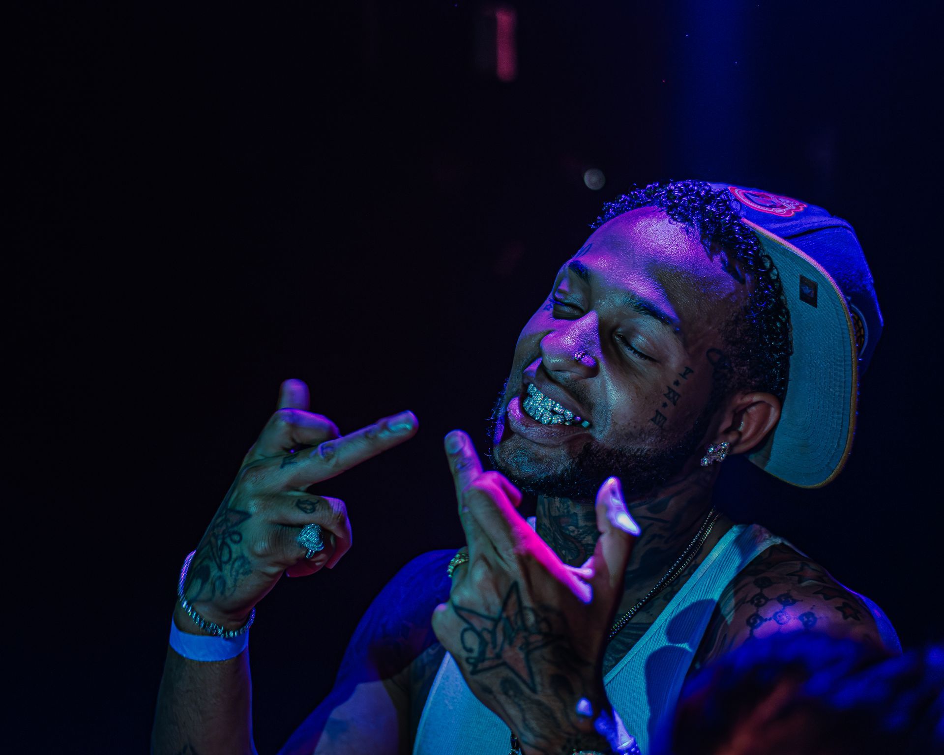 A man is making a peace sign with his hands in a dark room. Trevion500