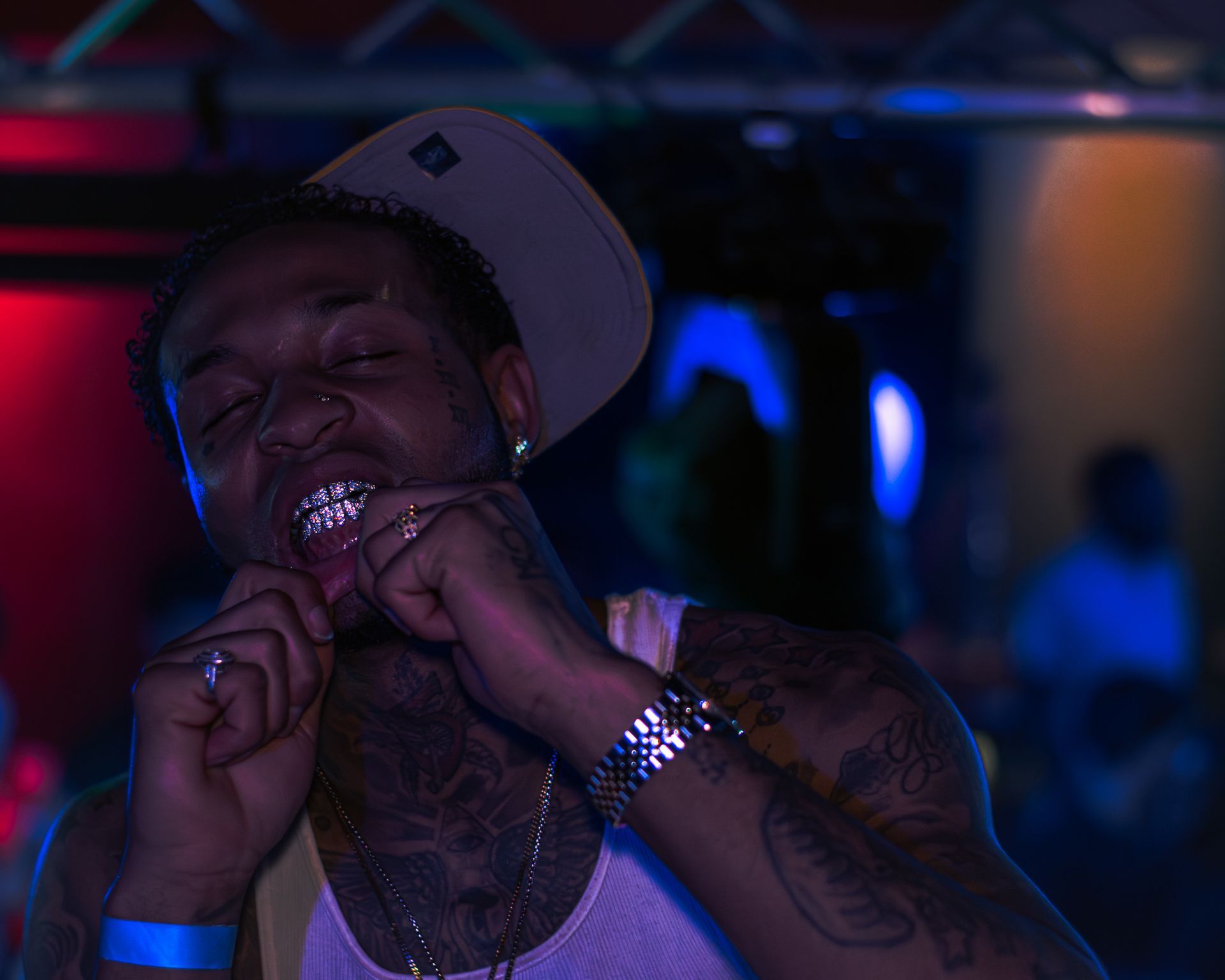 A man wearing a hat and a tank top is standing in a dark room. Trevion500