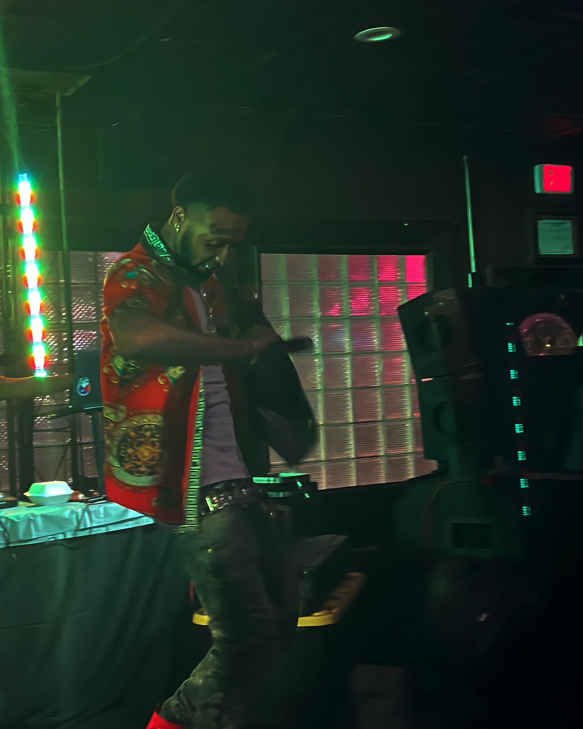 A man in a red shirt is playing a guitar in a dark room. Trevion500