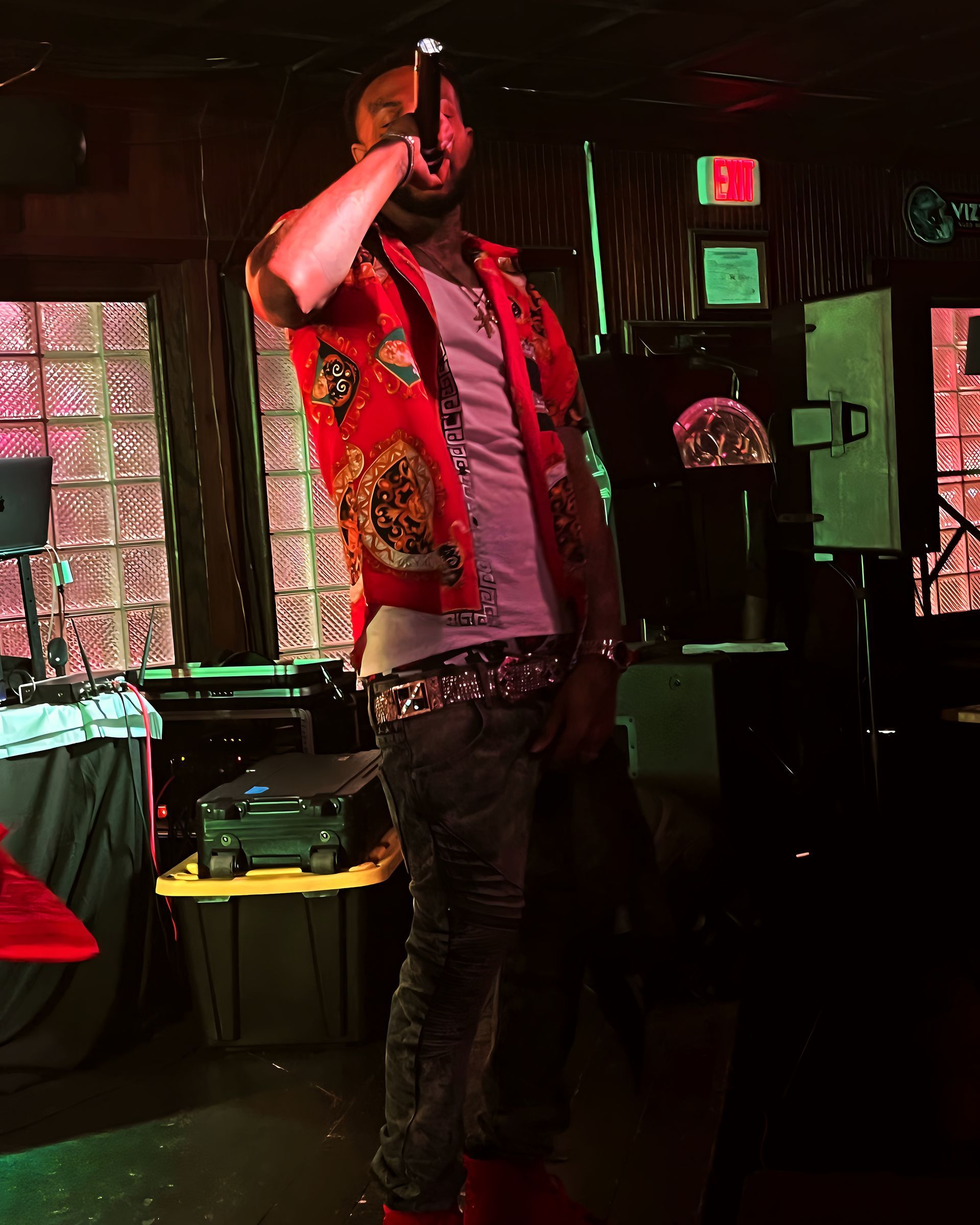 A man in a red shirt is singing into a microphone. Trevion500