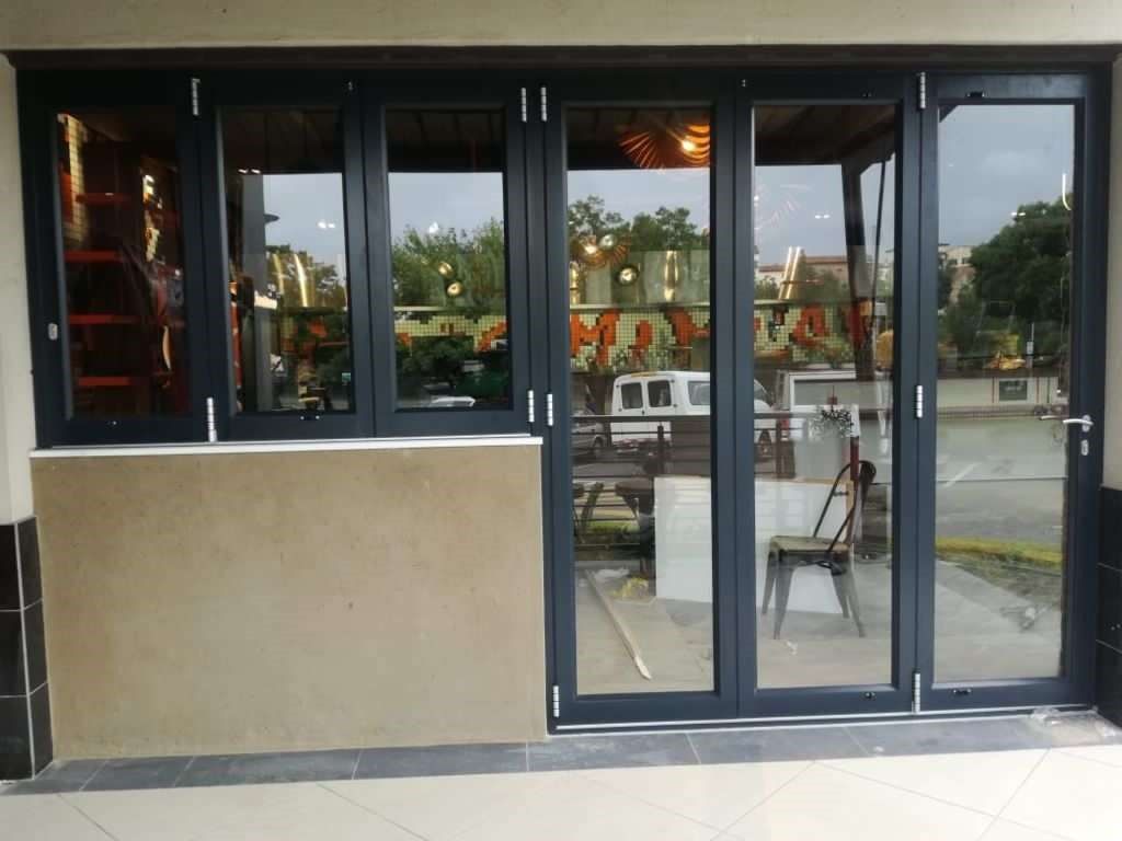 Black framed glass doors and windows on tan wall; storefront entrance.
