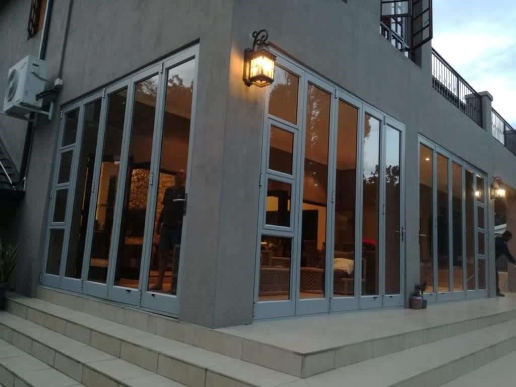 Exterior of a building with folding glass doors, a gray facade, and outdoor lighting.