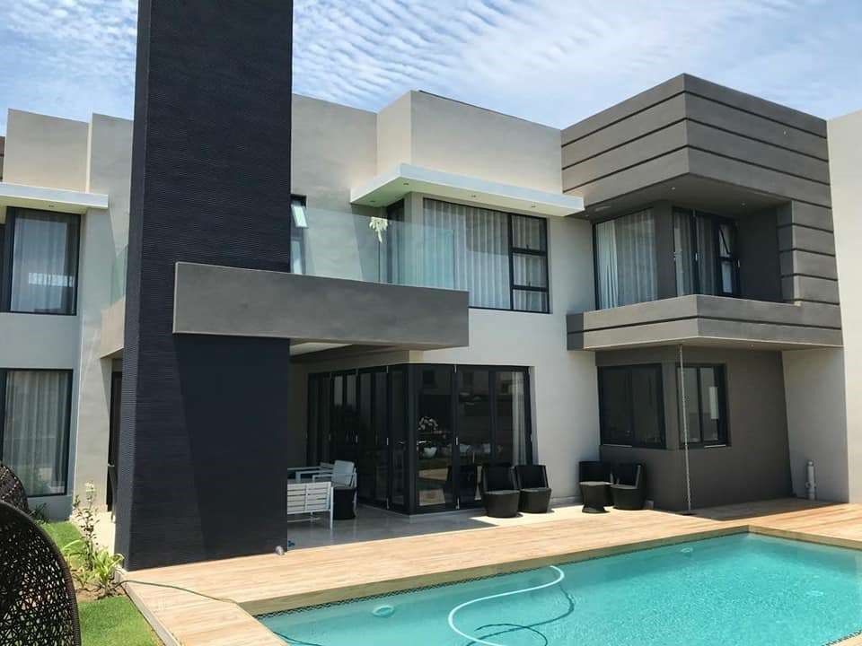 Modern two-story house with a pool, black and gray exterior, blue sky, and outdoor seating.
