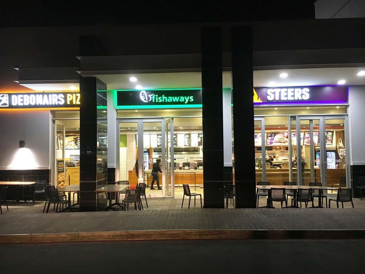 Nighttime exterior of Debonairs Pizza, Fishaways, and Steers restaurants.