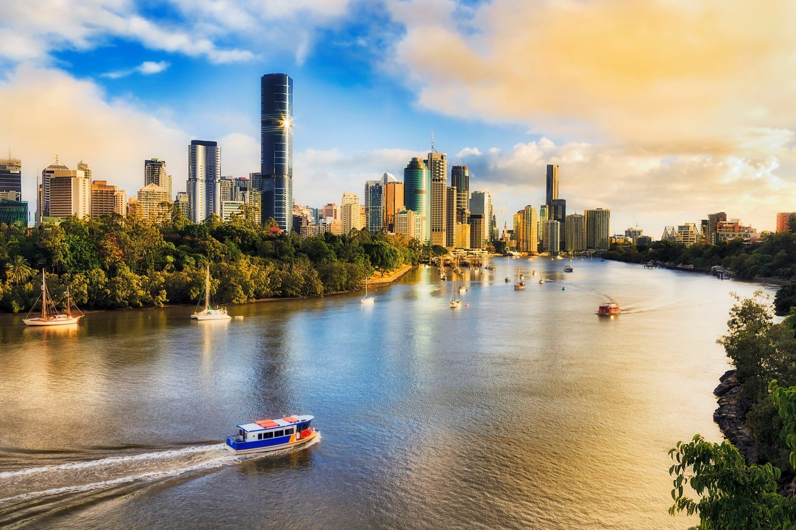 A boat is going down a river with a city skyline in the background.