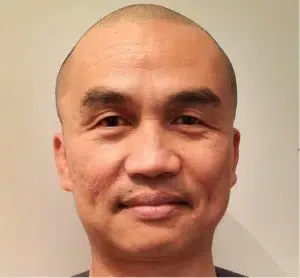 A bald man with a mustache is smiling for the camera.