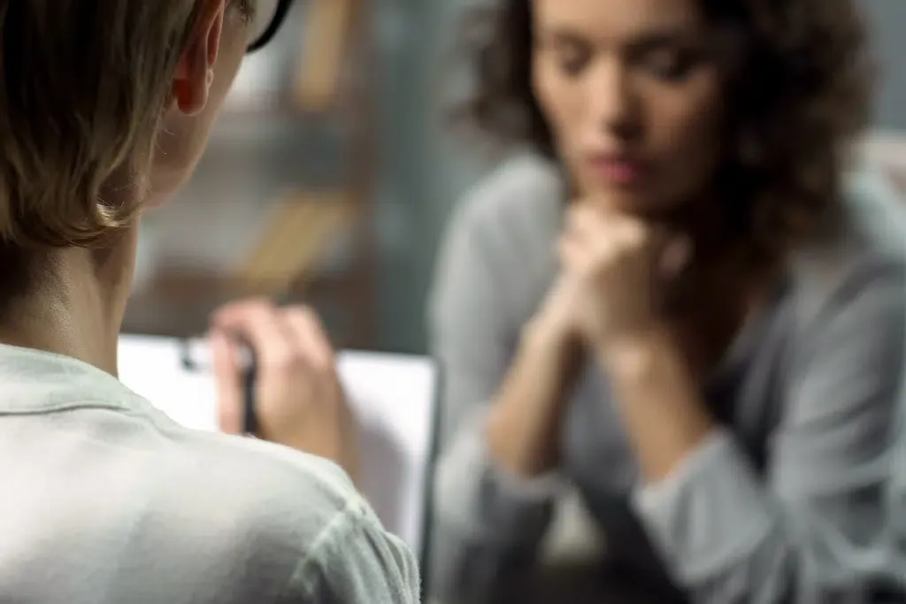 A woman is sitting at a table talking to a doctor.
