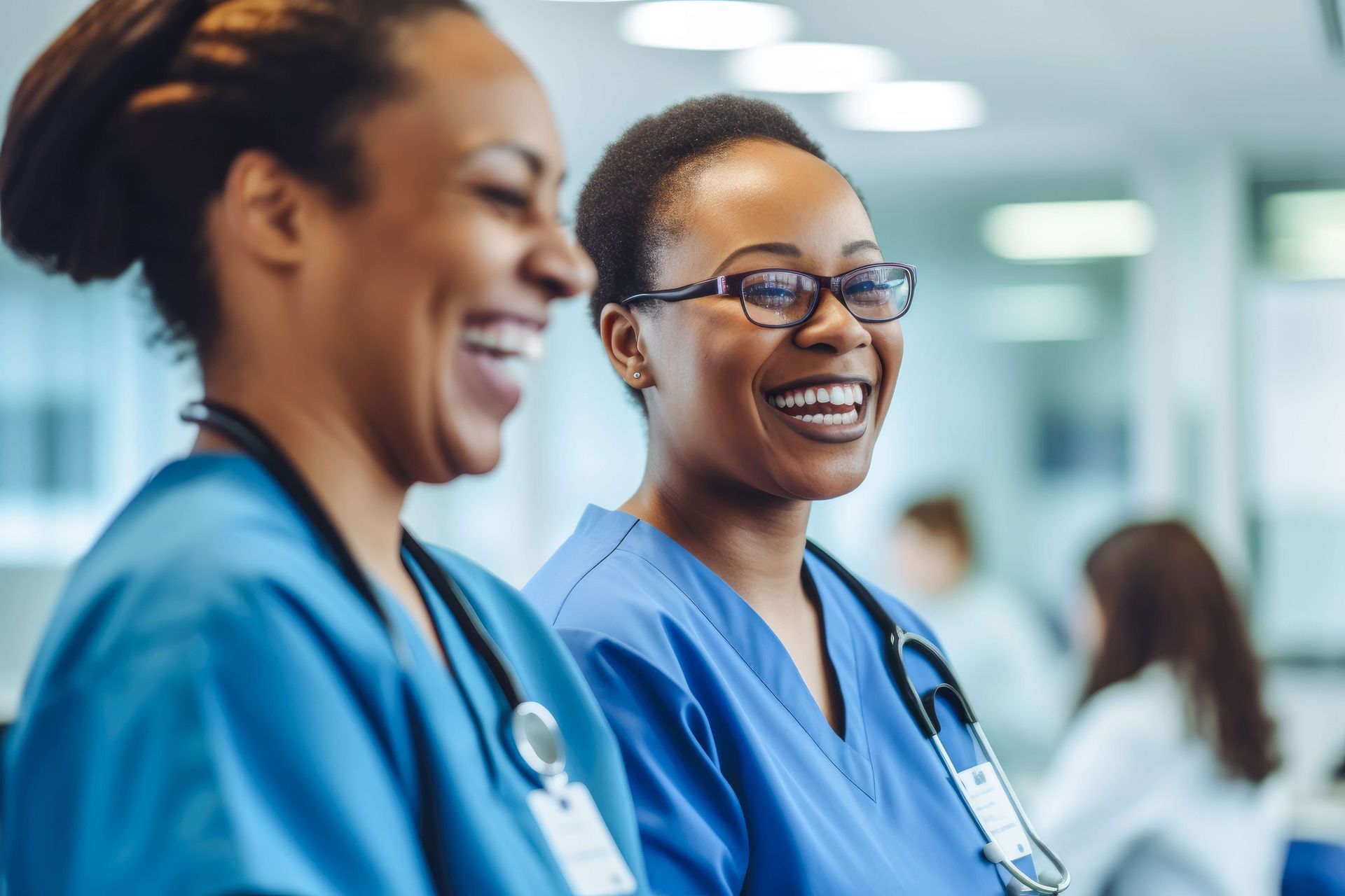 Two nurses are laughing together in a hospital room.