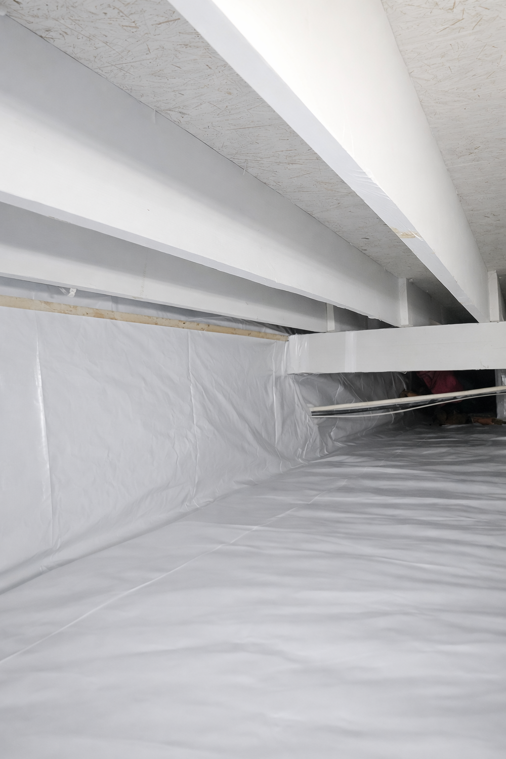 Corner of a basement with white walls and a concrete floor. A dark strip lines the floor where the walls meet.