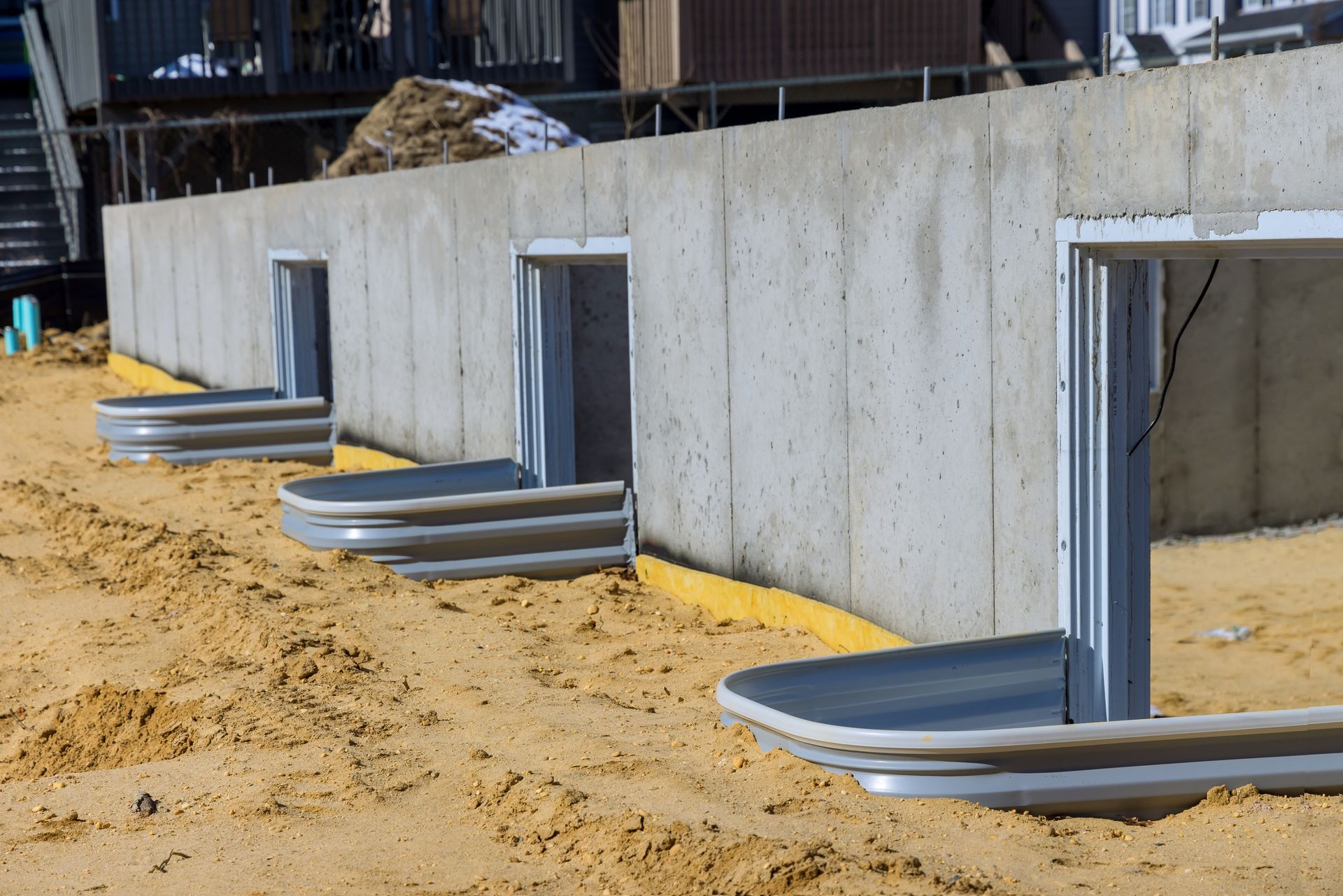 Concrete foundation with window wells in sandy soil.
