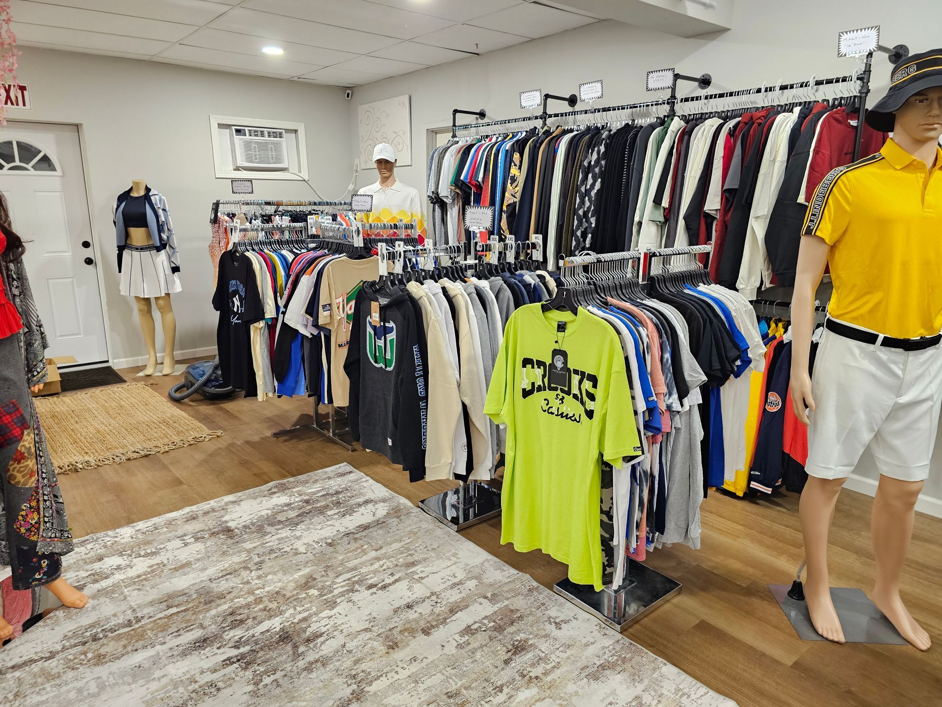 Clothing store interior featuring racks of apparel, including a bright neon green t-shirt, and mannequins displaying outfits.