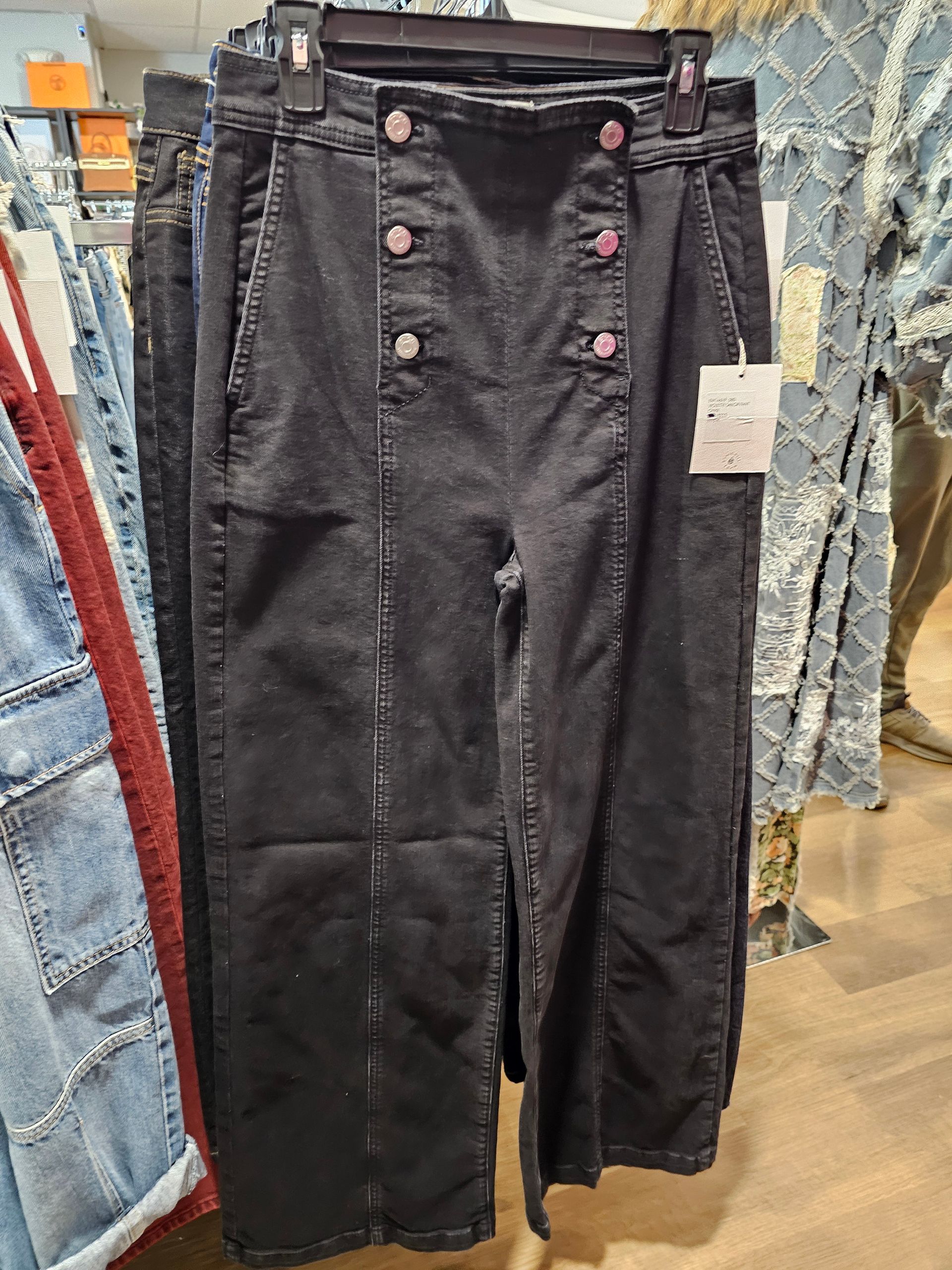 Black high-waisted denim pants with double-button sailor-style front closures and a vertical seam down each leg.