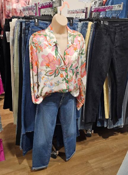 Mannequin in a floral print blouse and blue jeans, displayed in a clothing store.