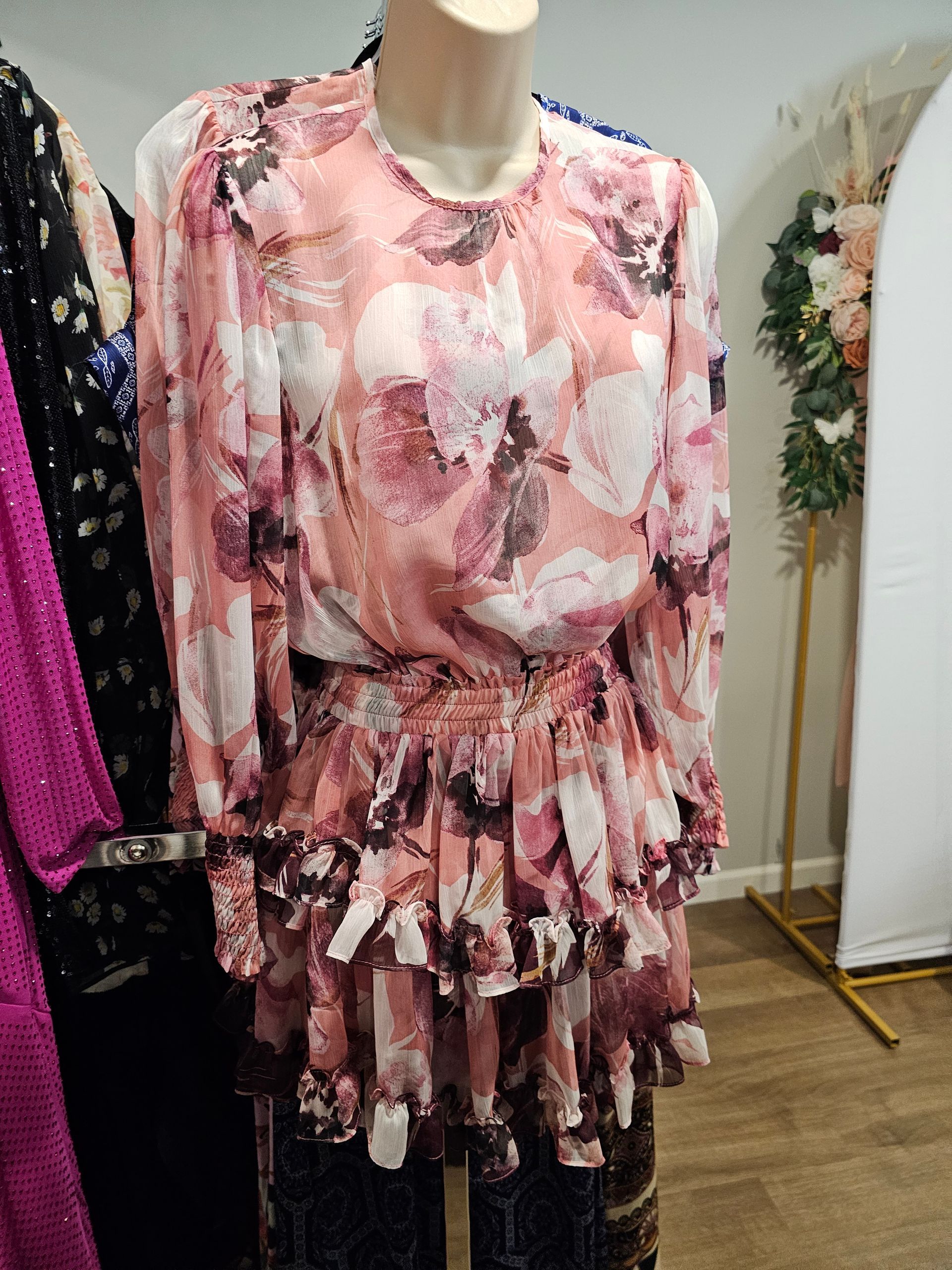 Woman in beige dress with intricate lace detailing, hands resting on chest and stomach.