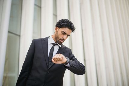 A man in a suit and tie is looking at his watch.