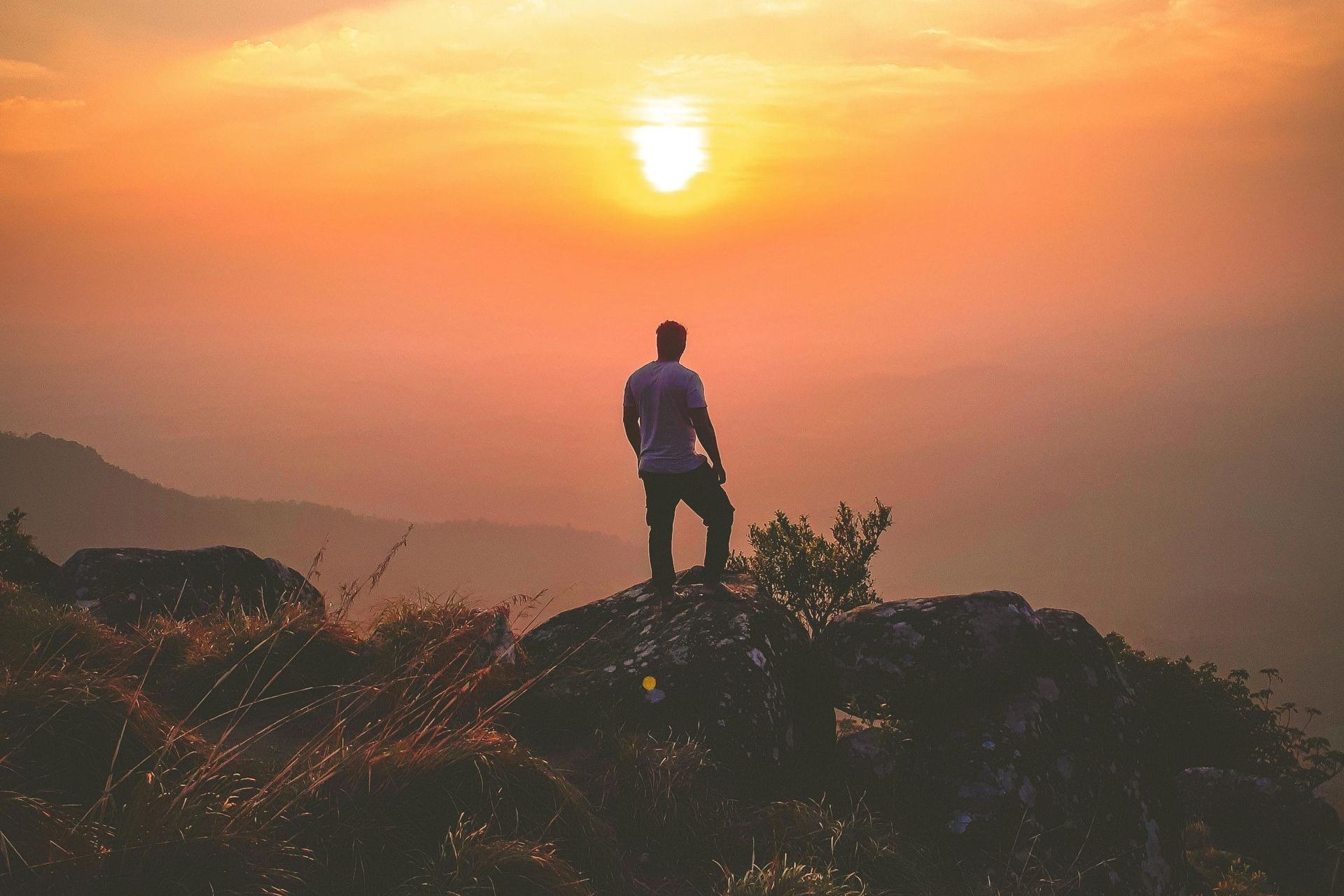 Two women with backpacks are walking down a path in the mountains.