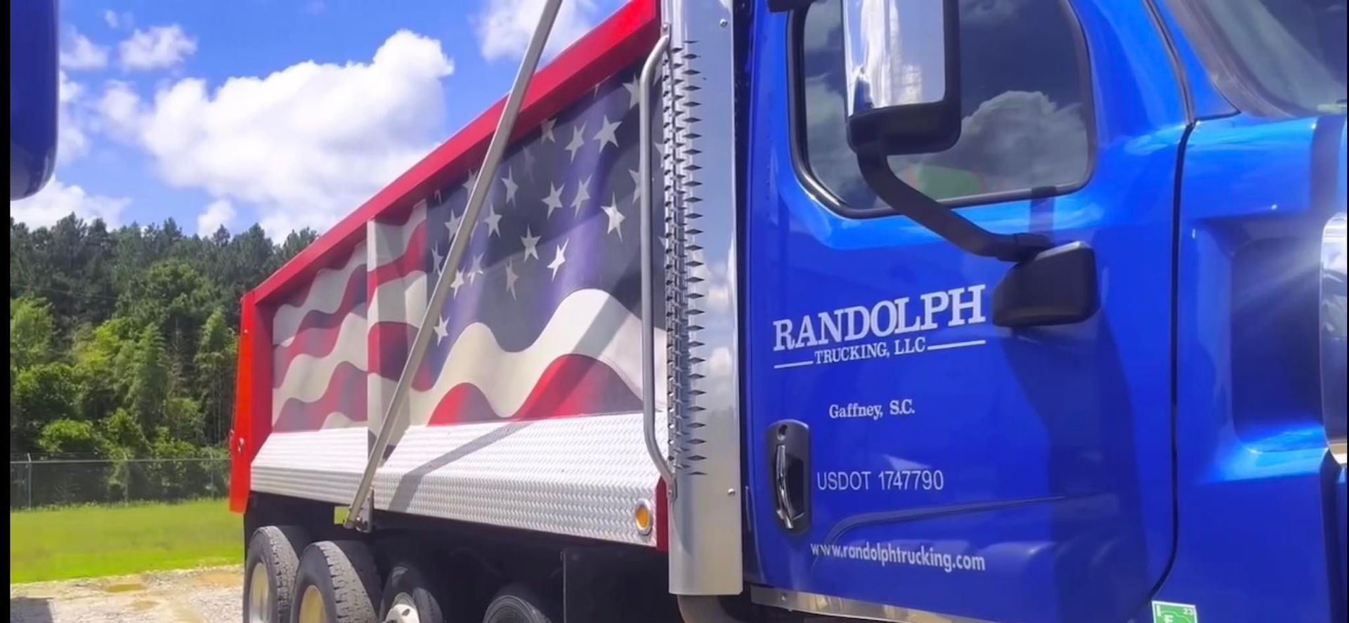Blue semi-truck with an American flag painted on its bed.