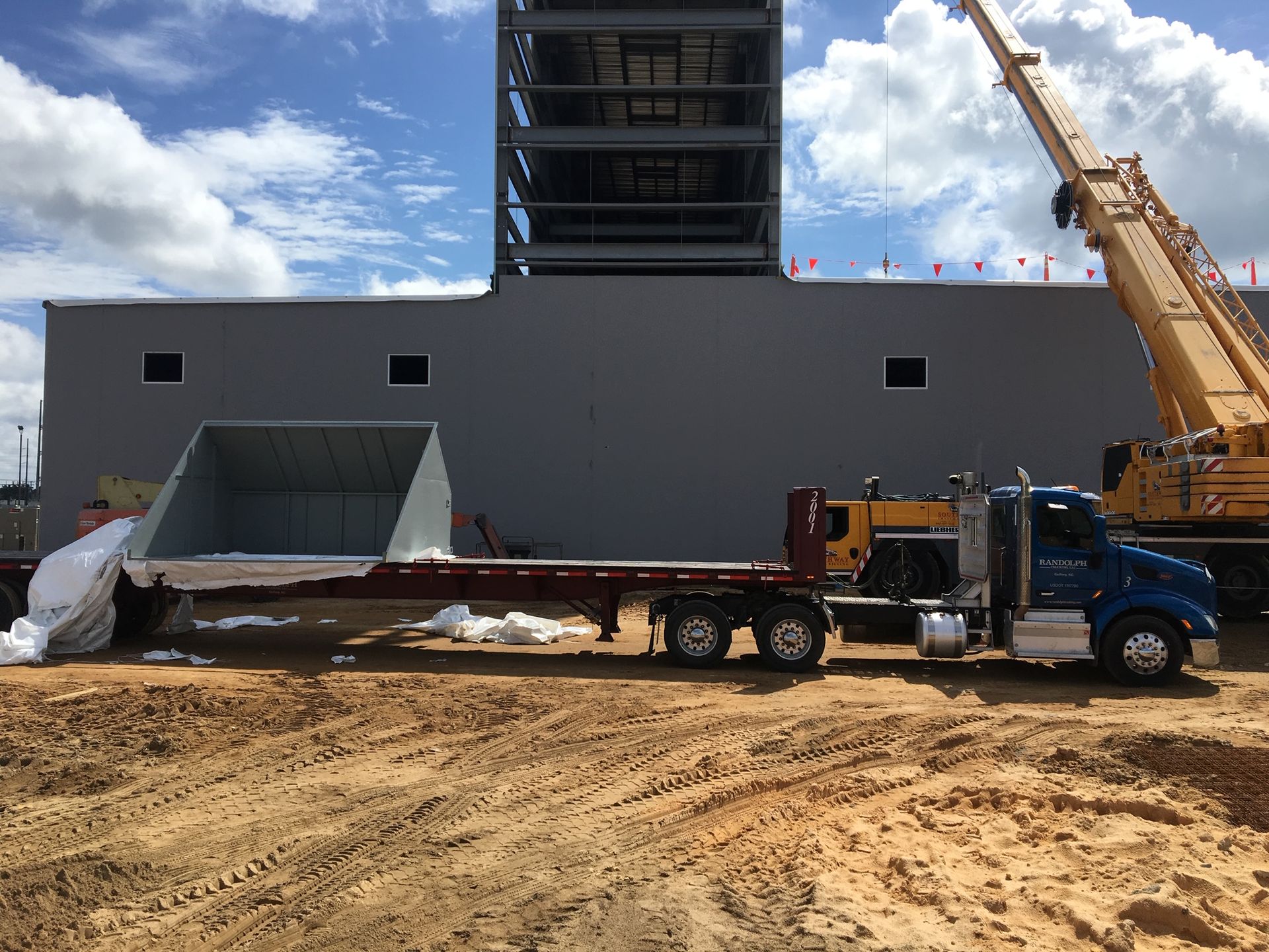 Blue and white dump truck parked on grass under a cloudy sky.