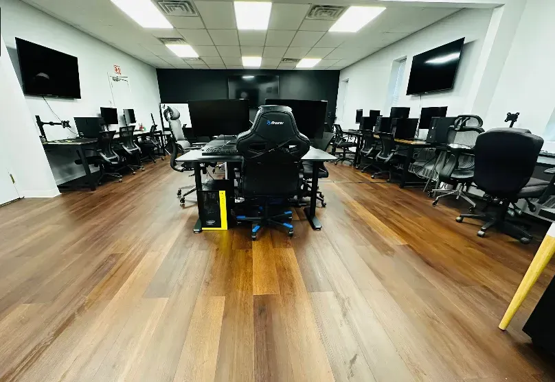 Gaming room with multiple computers and monitors on wooden floors.