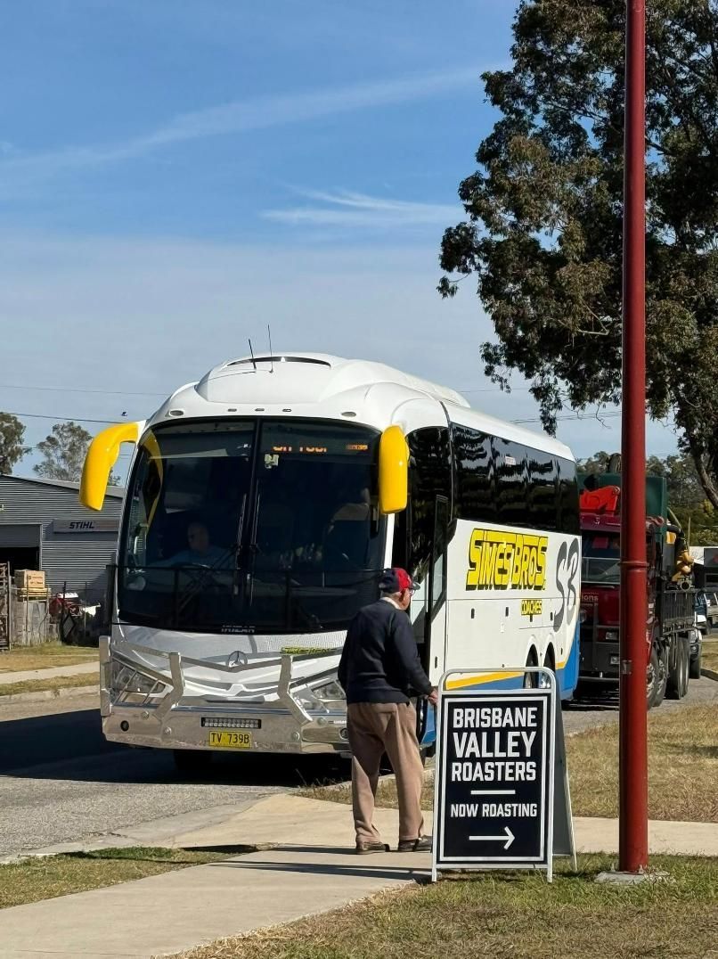 A Bus Is Parked on The Side of The Road Next to A Sign — Simes Bros Coaches in South Lismore, NSW