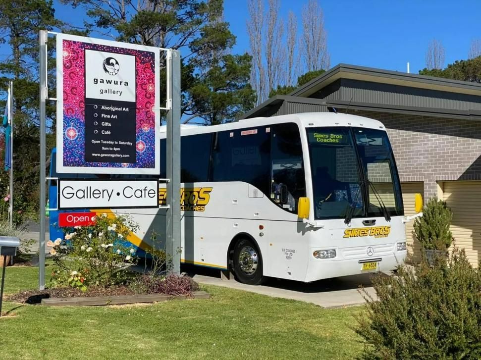 A White Bus Is Parked in Front of A Sign that Says Gallery Cafe — Simes Bros Coaches in South Lismore, NSW