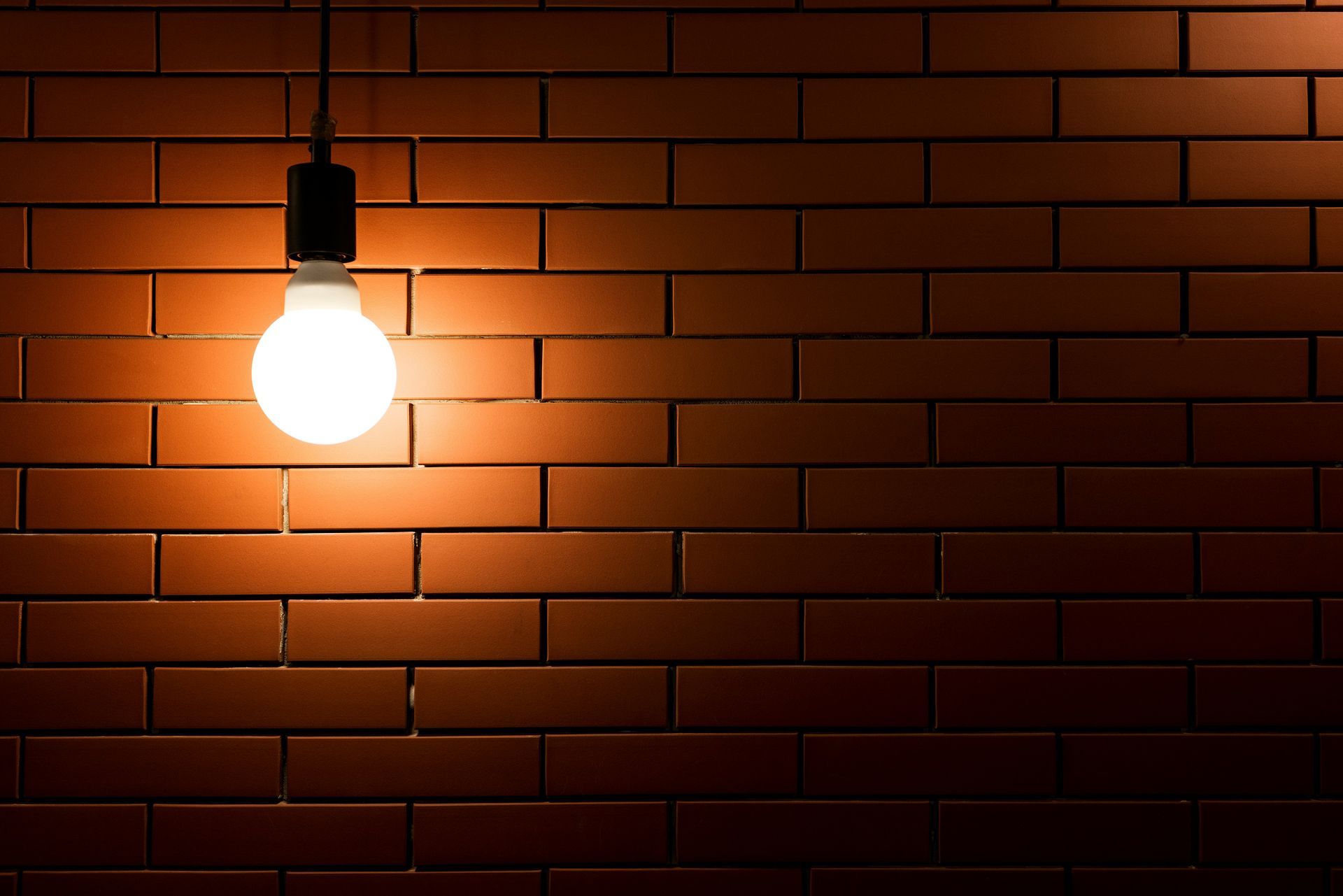 A single light bulb illuminating a brick wall, representing insight and understanding.