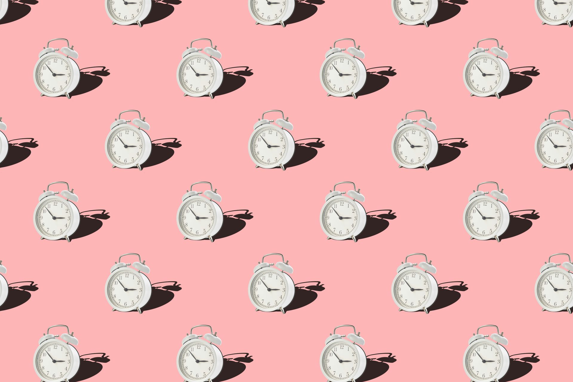 Rows of white alarm clocks on a pink background symbolize repeated patterns and daily habits.