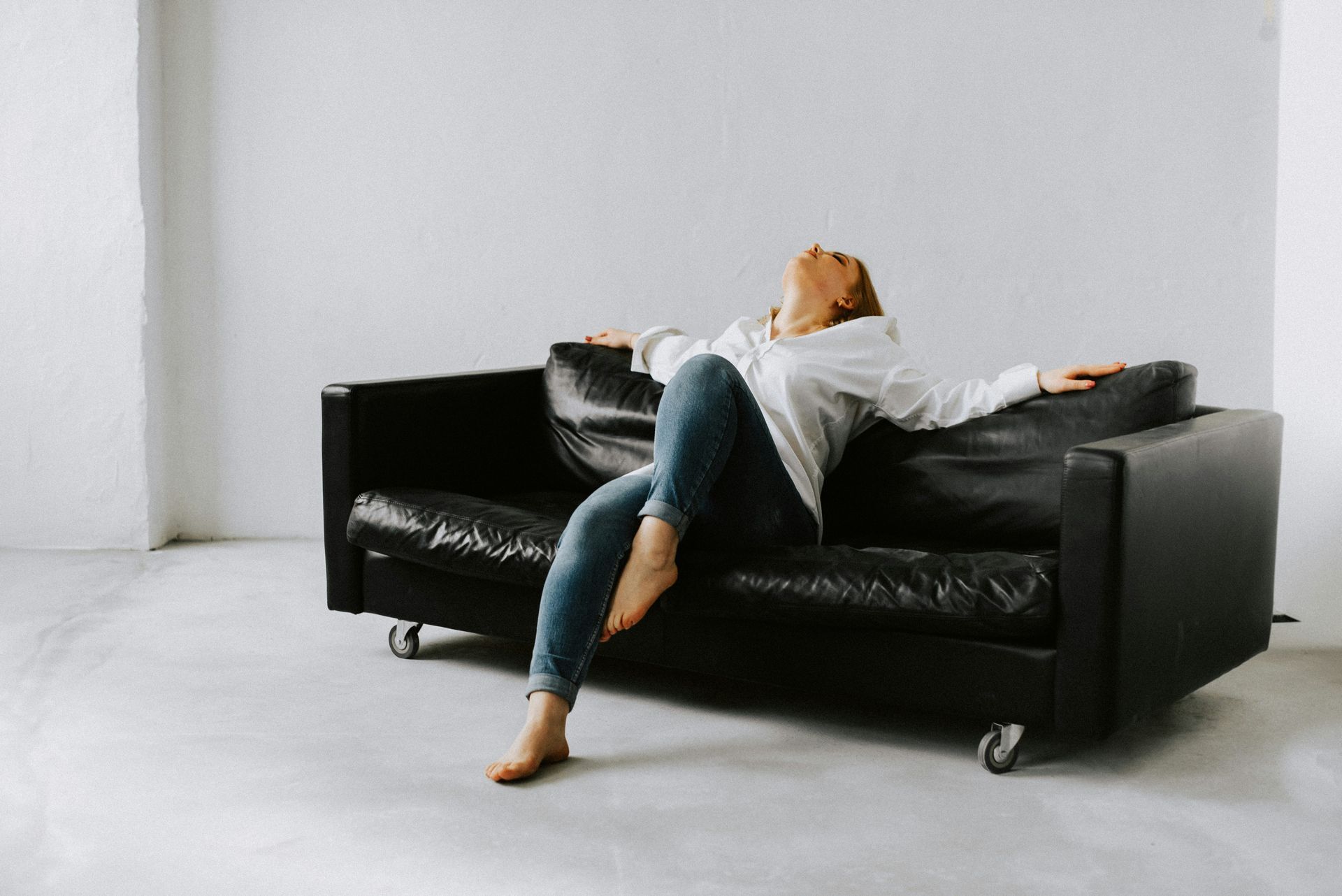 A woman lying back on a couch, looking physically exhausted.
