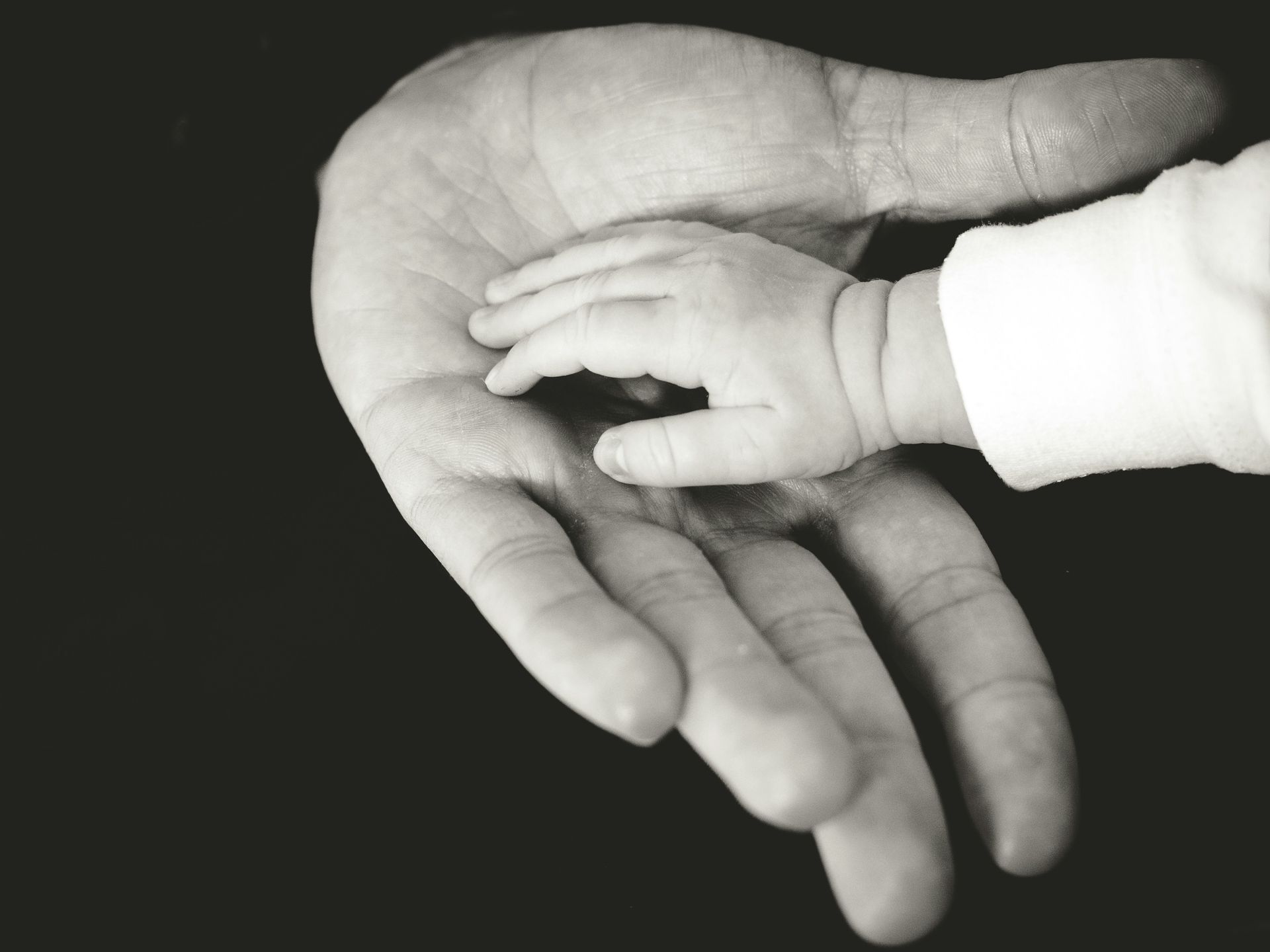 Close-up of a child’s hand resting in an adult’s open hand.