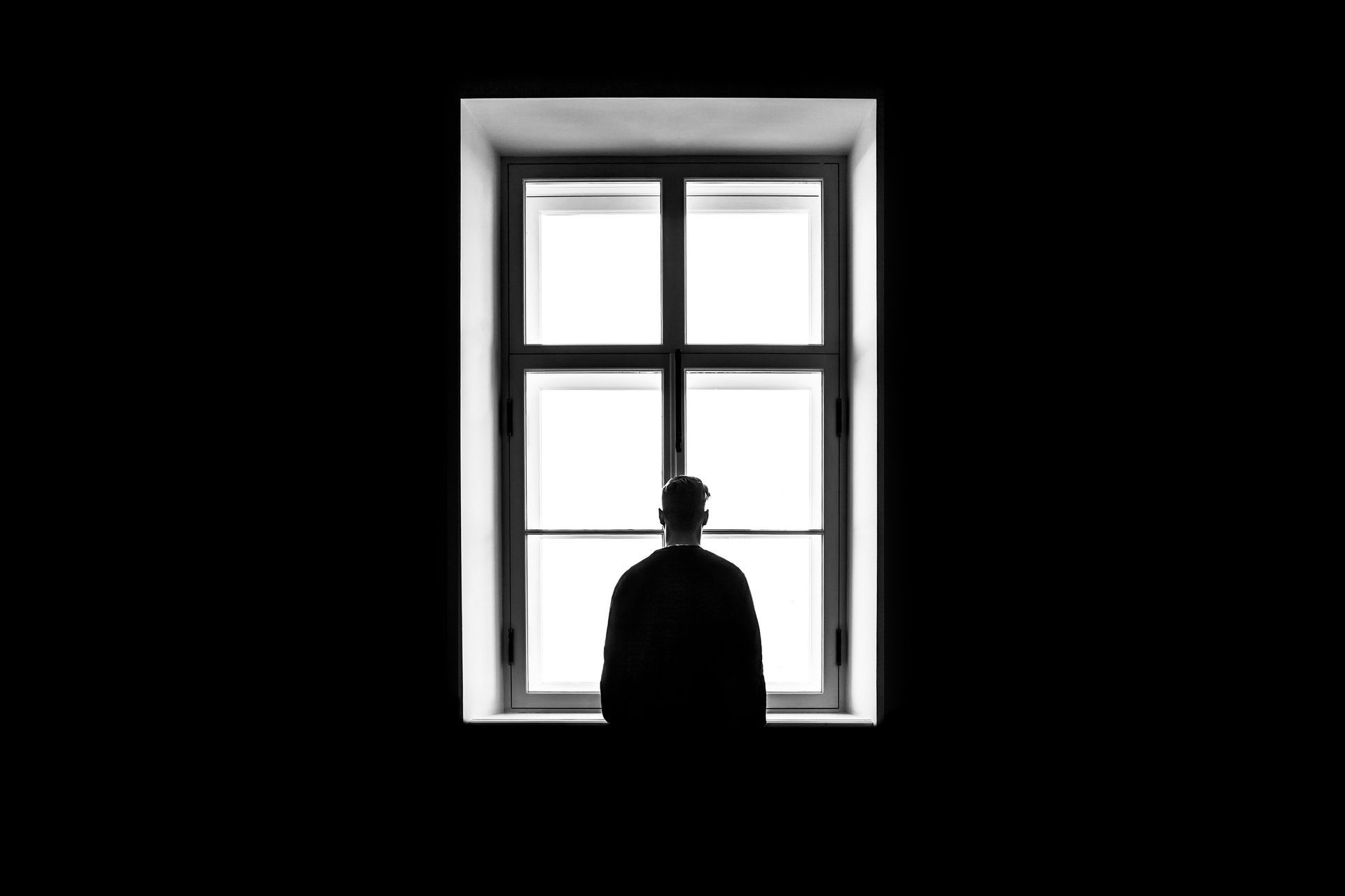 An individual standing before a window, illustrating the pain of emotional disconnection in family relationships.