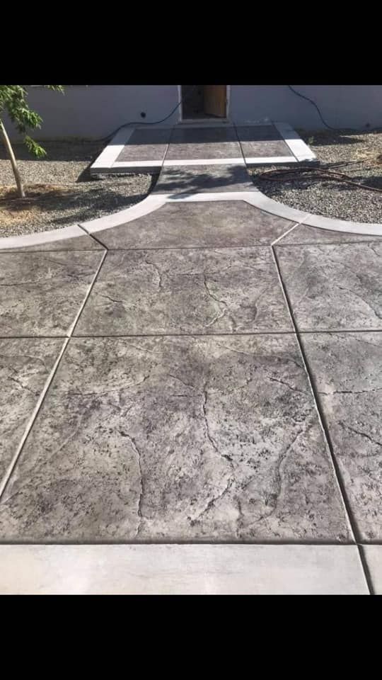 Concrete walkway leading to a front door ramp with white painted guidance lines in a sunny yard