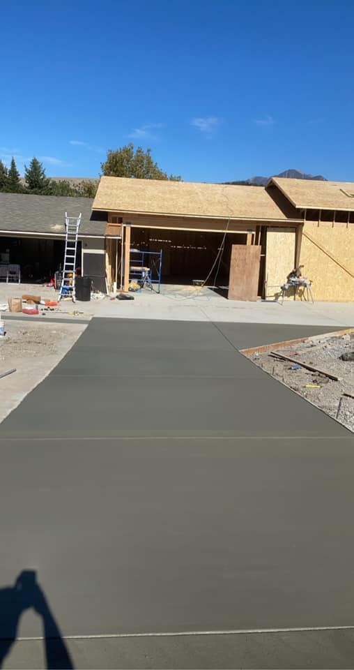 New concrete driveway leading to a house under construction on a sunny day