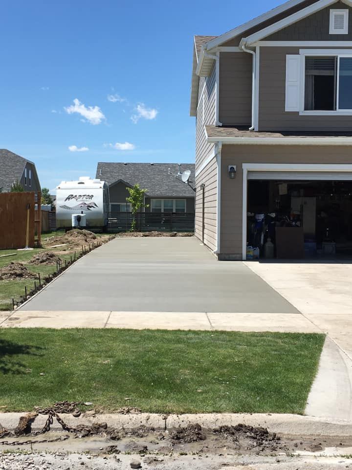 Residential driveway beside a two-story house, with a garage and lawn under a blue sky.
