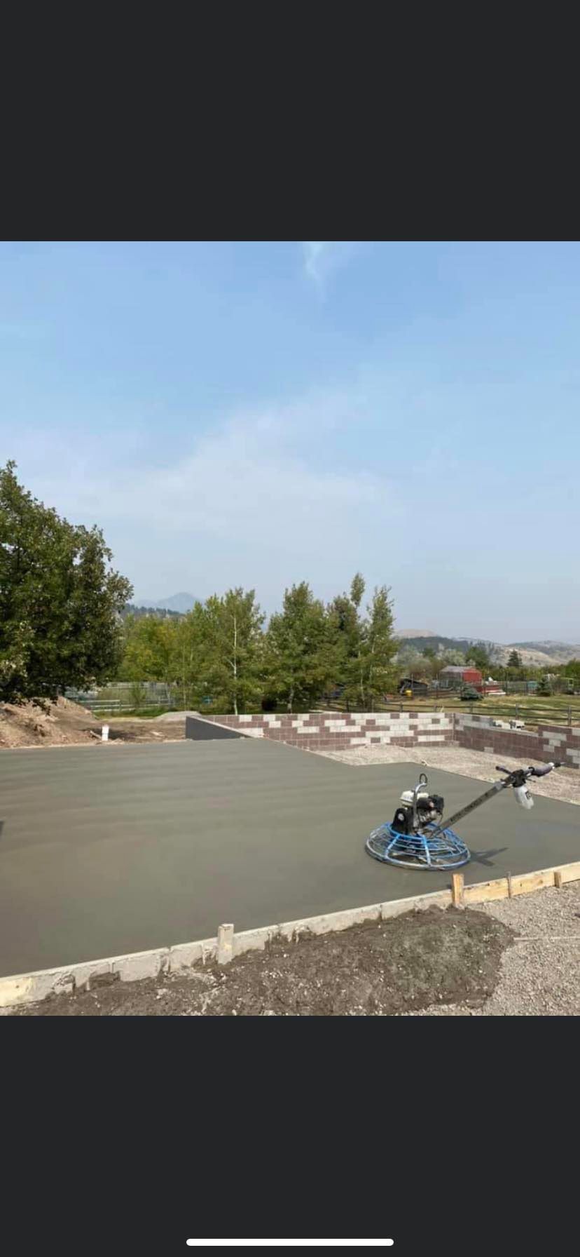 Person riding a blue scooter on a curved road beside a rocky landscape under a clear sky