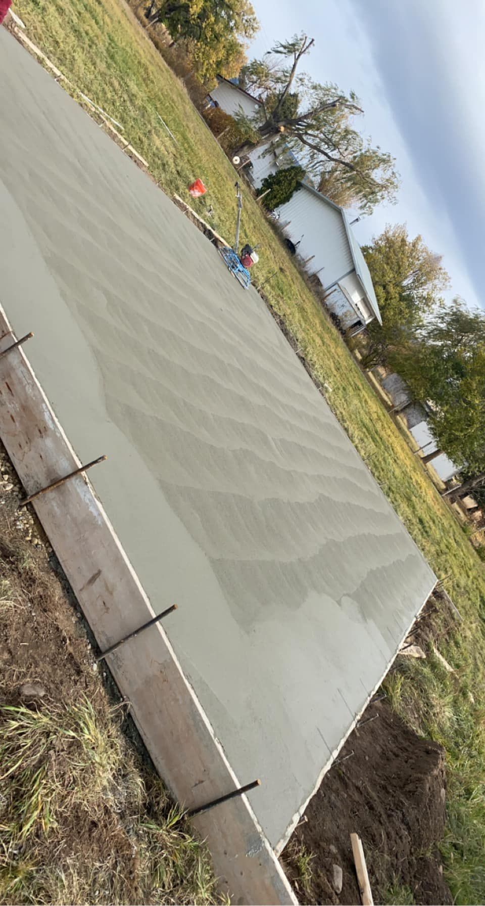Freshly poured concrete slab with wet surface in a grassy outdoor construction area