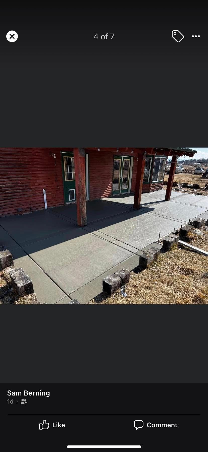 Covered walkway beside a red building with concrete sidewalk and posts, overlooking a snowy landscape