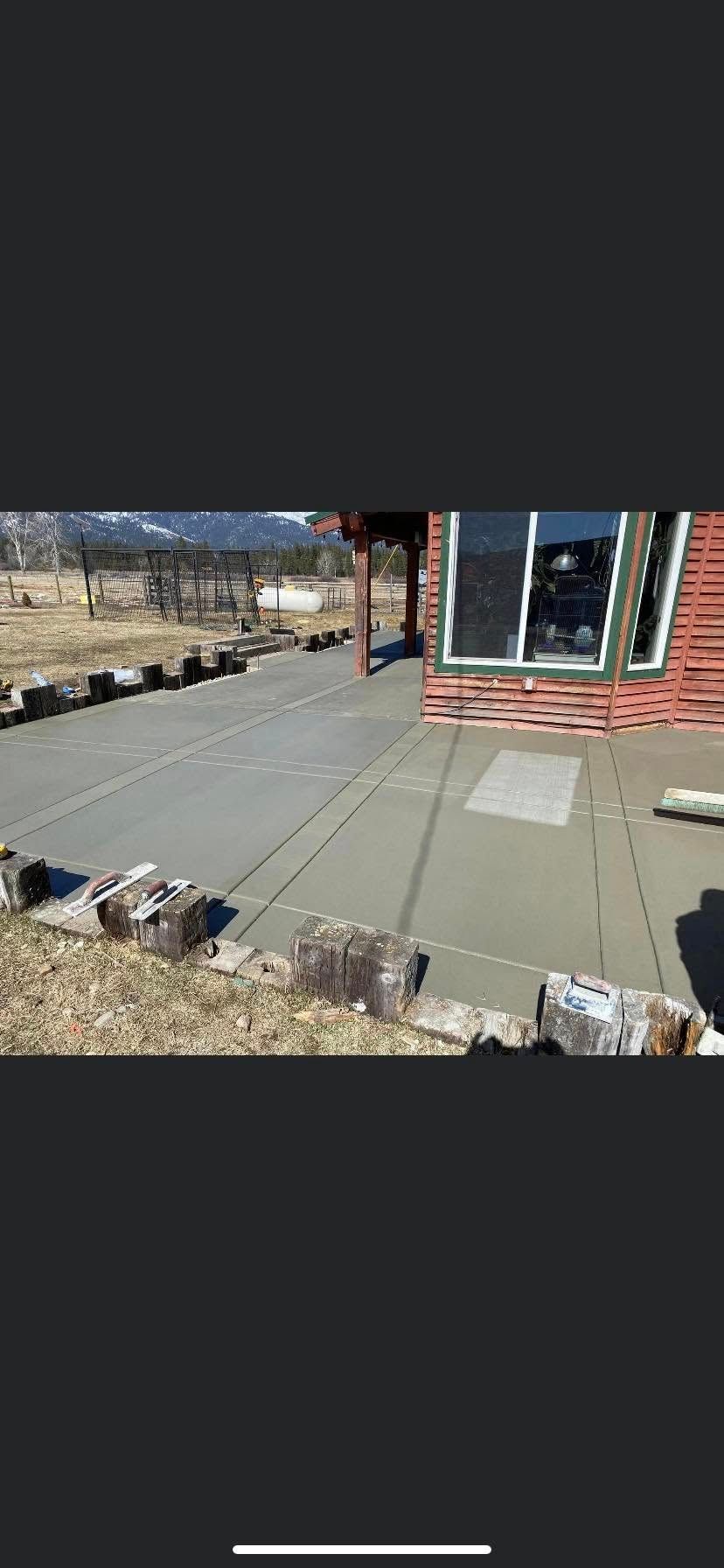 A house patio with gray pavers, stone border, and a glass door beside a brick wall.