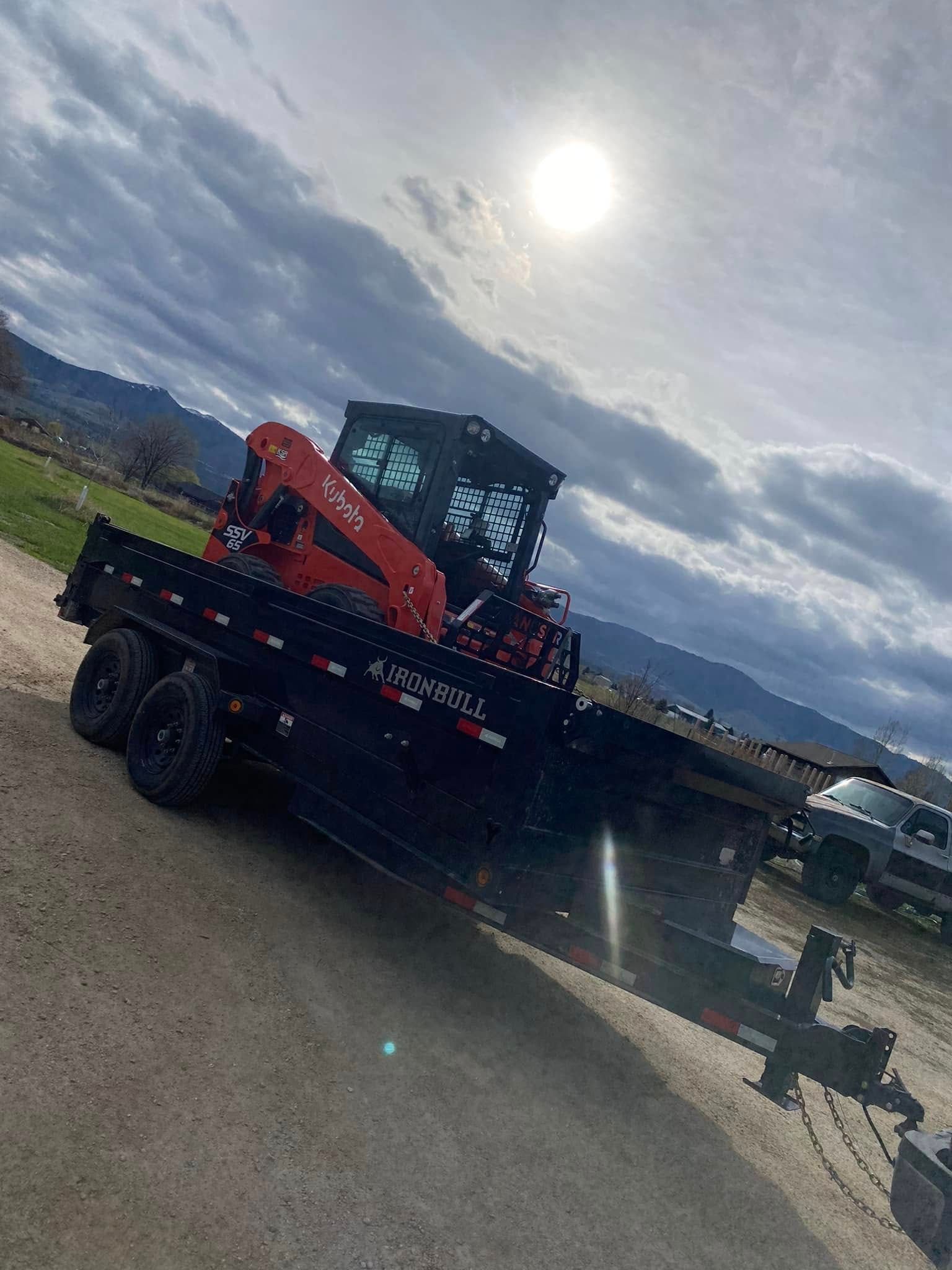 Tow truck with orange boom parked on roadside under bright sun, with mountains in the background.