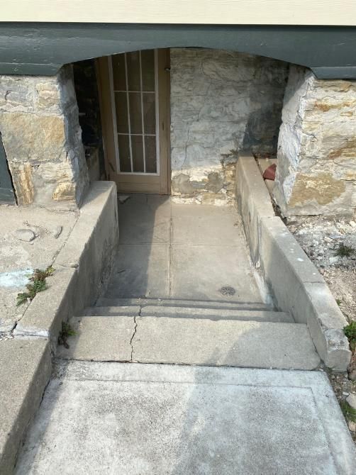 Narrow concrete ramp leading to a barred doorway between stone walls