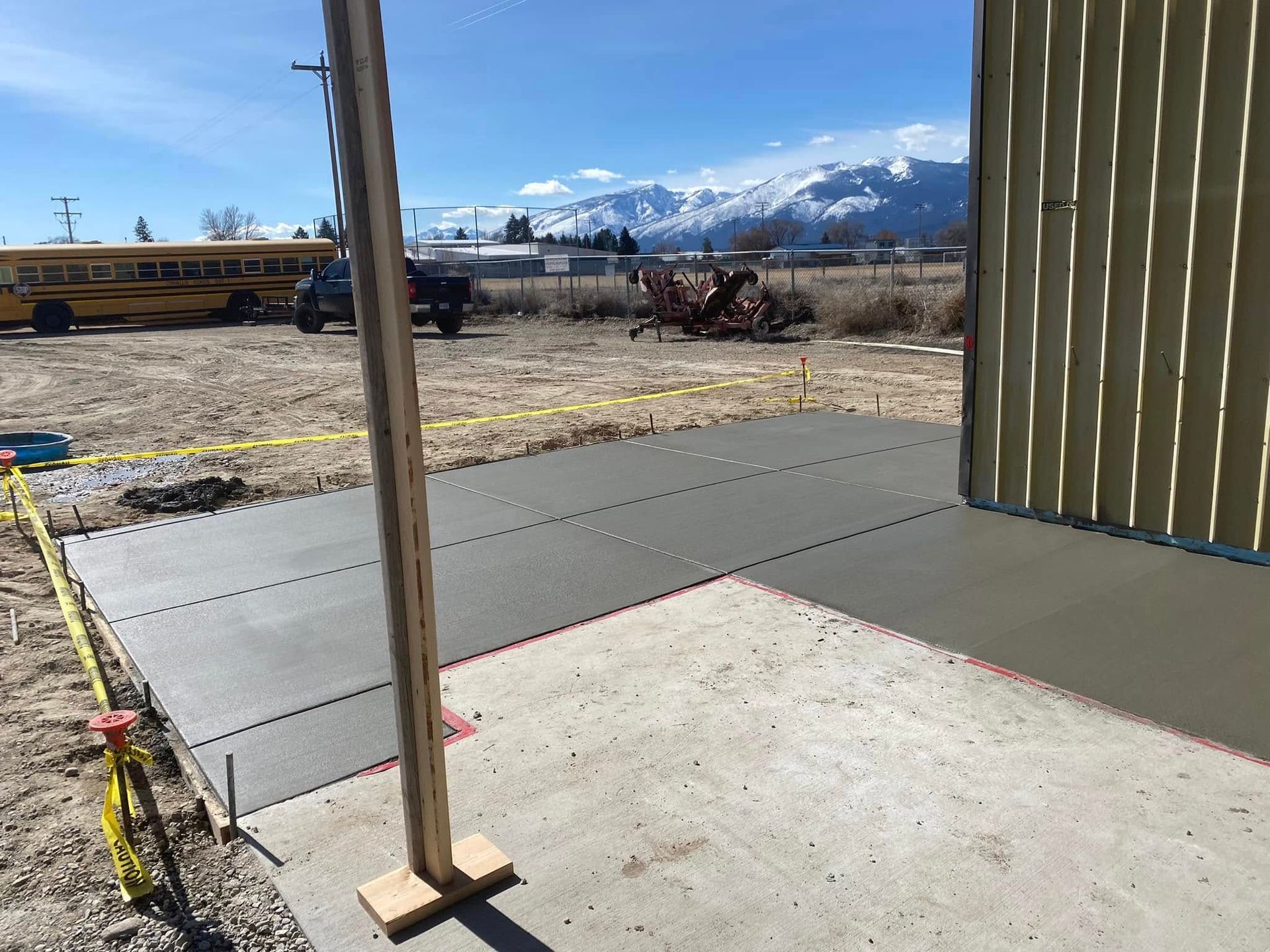 Construction site with concrete slab, yellow caution tape, and mountains in the background