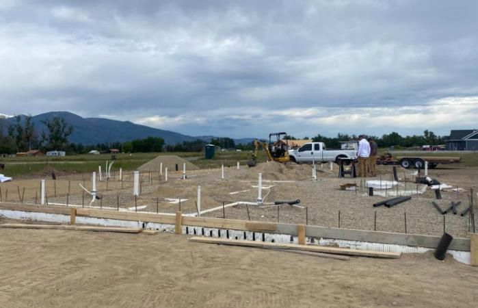 Construction site with concrete foundation forms on a sandy lot under cloudy skies