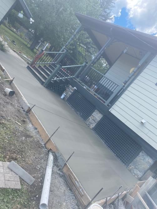 House with front porch and wheelchair ramp beside a concrete walkway under construction