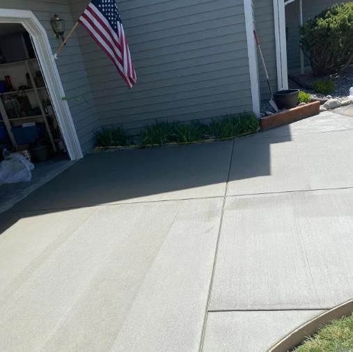 Concrete driveway beside a house with an American flag hanging near the garage.