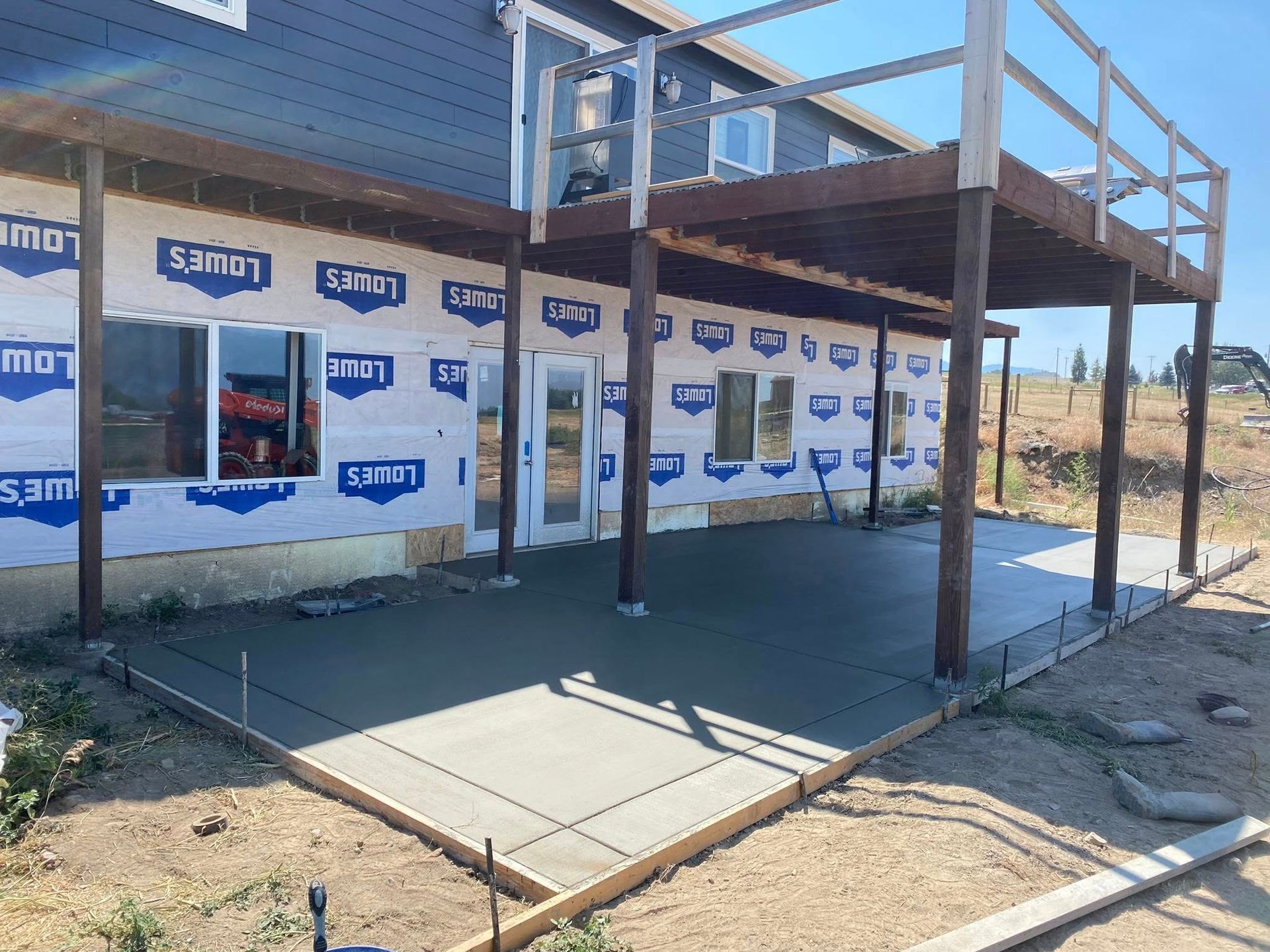 Partially built house with wood deck and concrete slab, wrapped in house sheathing under construction