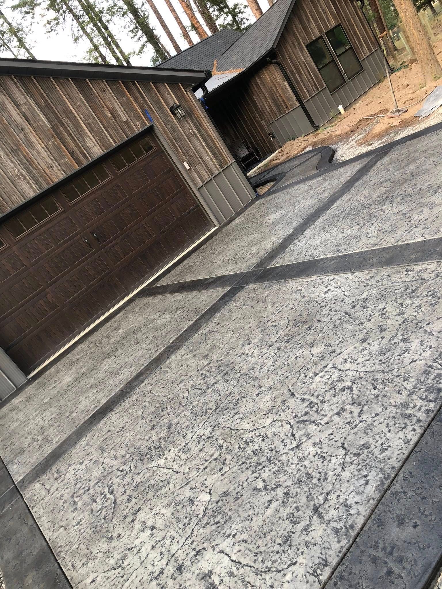 Tilted view of a brick building, paved driveway, and garage doors in a quiet outdoor area