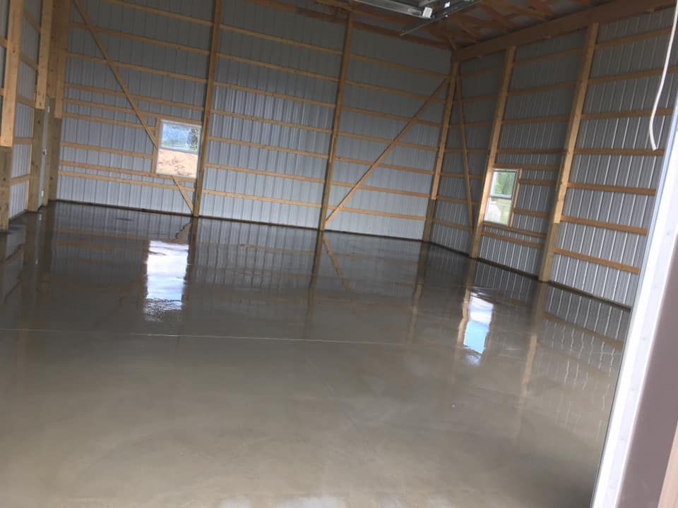 Empty metal shed with a wet concrete floor and light from small windows