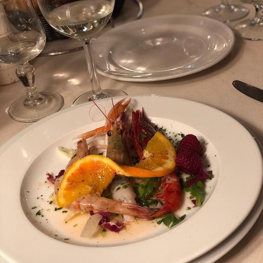 Un piatto di cibo con gamberetti e arance su un tavolo