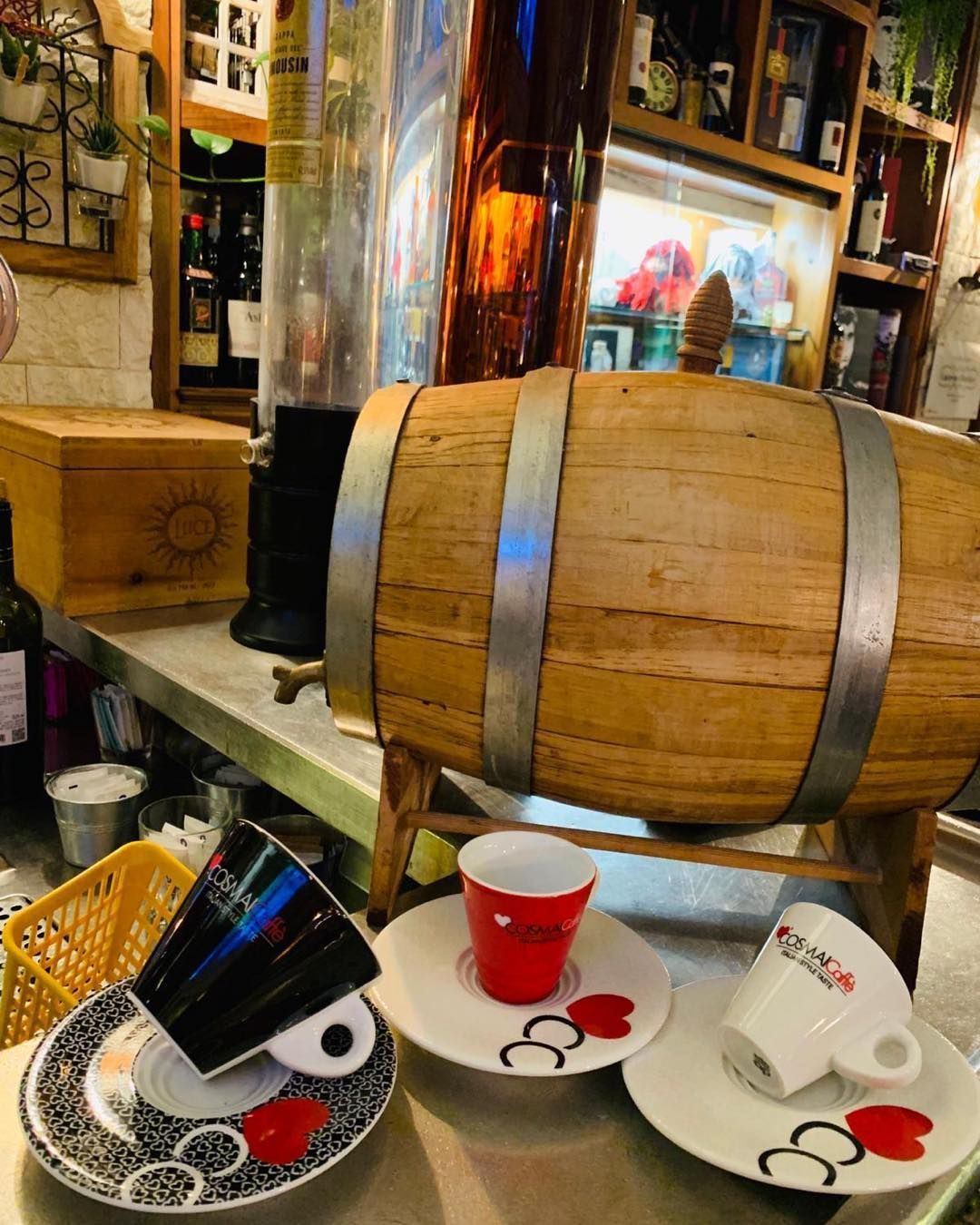 Una botte di legno è appoggiata su un bancone accanto a tazze e piattini