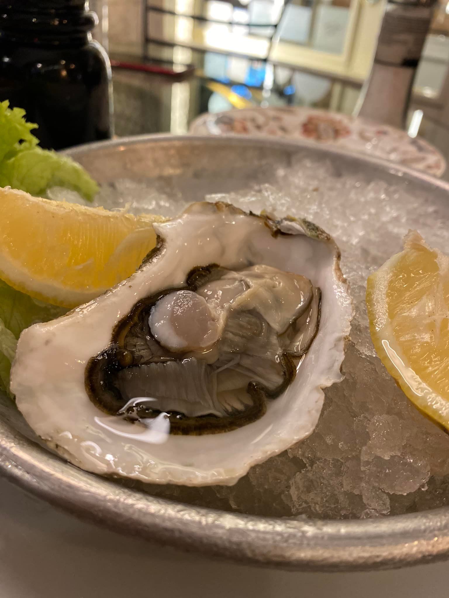 Un primo piano di un'ostrica su ghiaccio con fette di limone su un piatto.