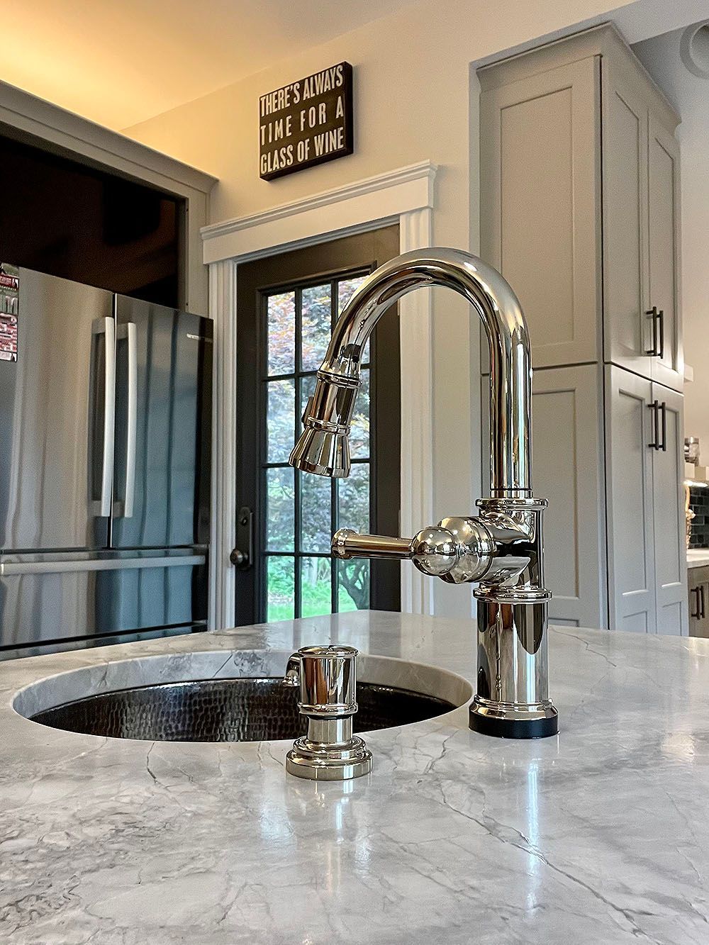 A kitchen sink with a faucet and a refrigerator in the background.